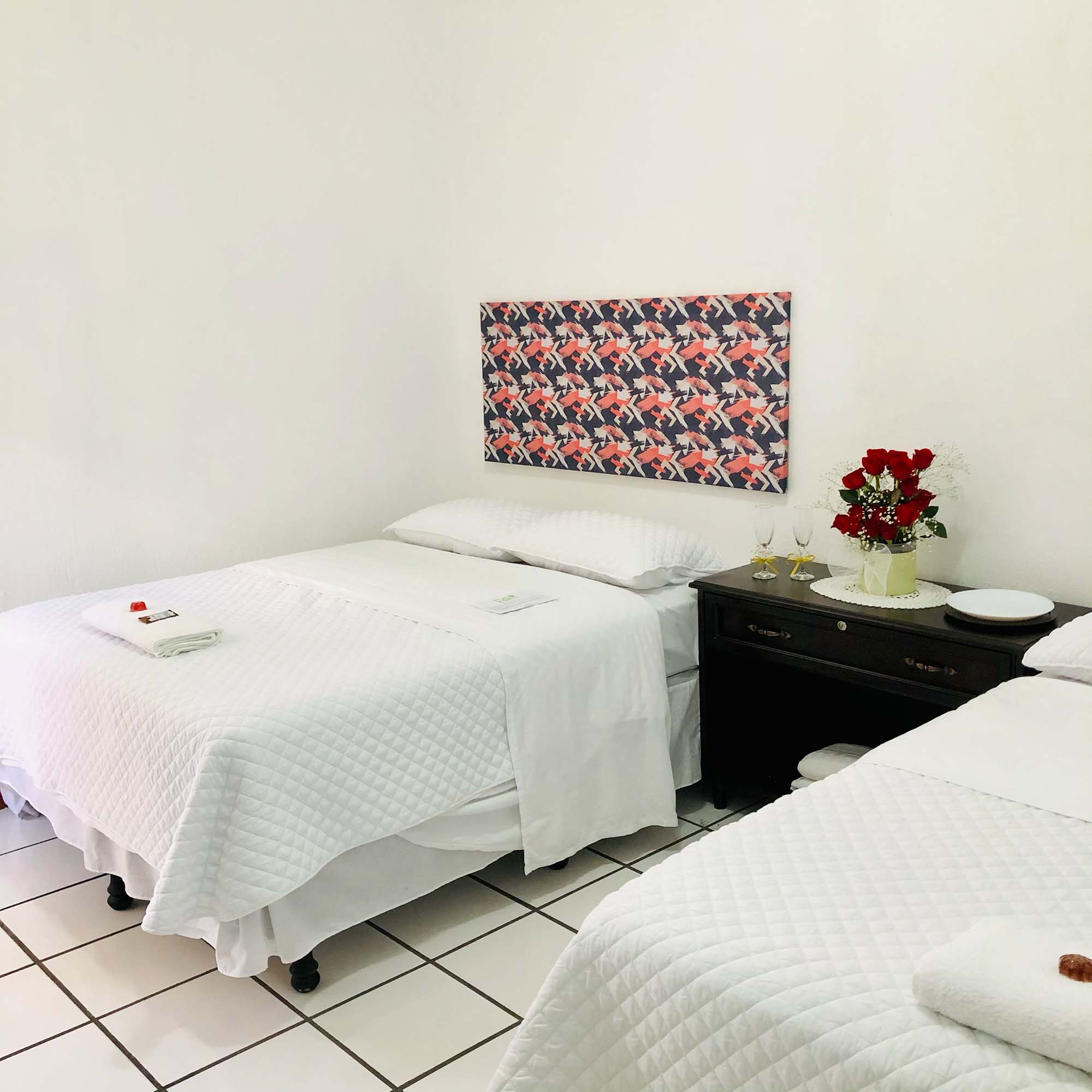 Habitación con camas dobles y rosas rojas